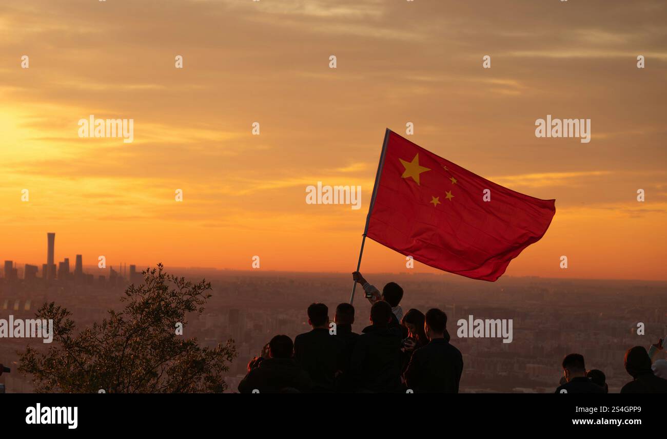 Un gruppo di patrioti cinesi che sventolano una bandiera cinese con onore al tramonto Foto Stock
