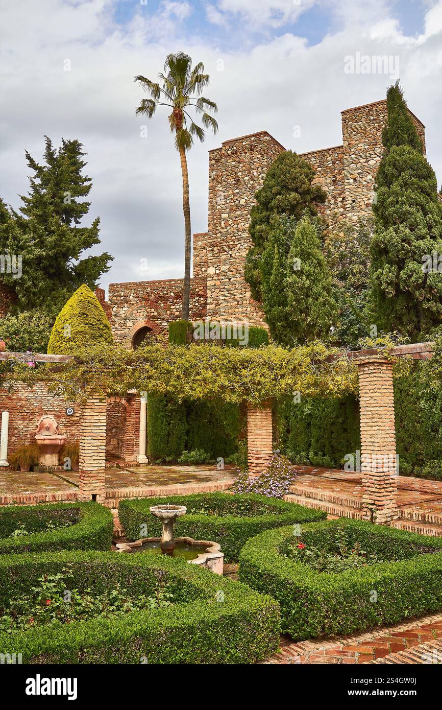 Giardino storico al Castello di Gibralfaro, Malaga con antiche mura di pietra e vegetazione sotto cieli limpidi Foto Stock