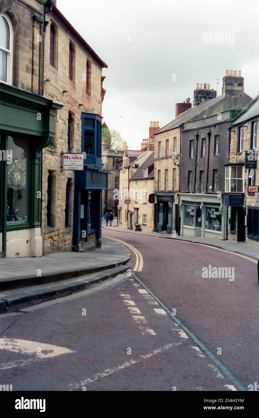 Una strada tortuosa con negozi nella città mercato di Alnwick nella contea di Northumberland, Inghilterra. Foto Stock