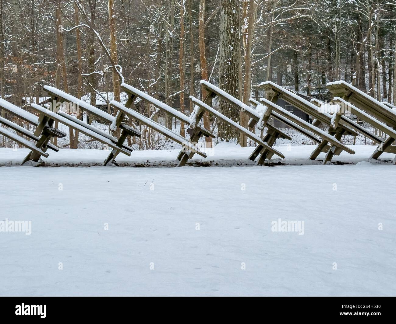 Foto di tavoli da picnic impilati ricoperti di neve in un parco durante la stagione invernale. Foto Stock