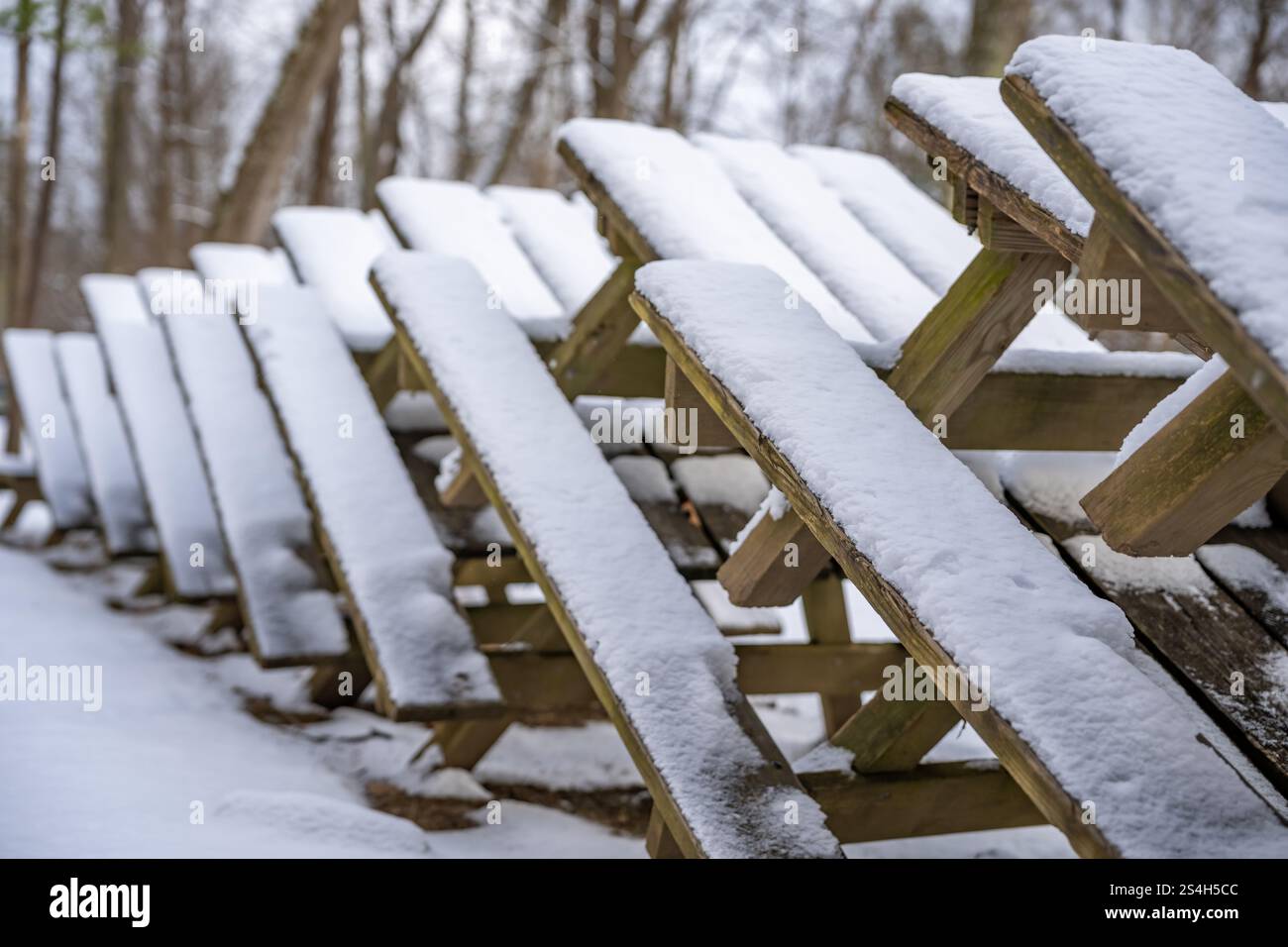 Foto di tavoli da picnic impilati ricoperti di neve in un parco durante la stagione invernale. Foto Stock
