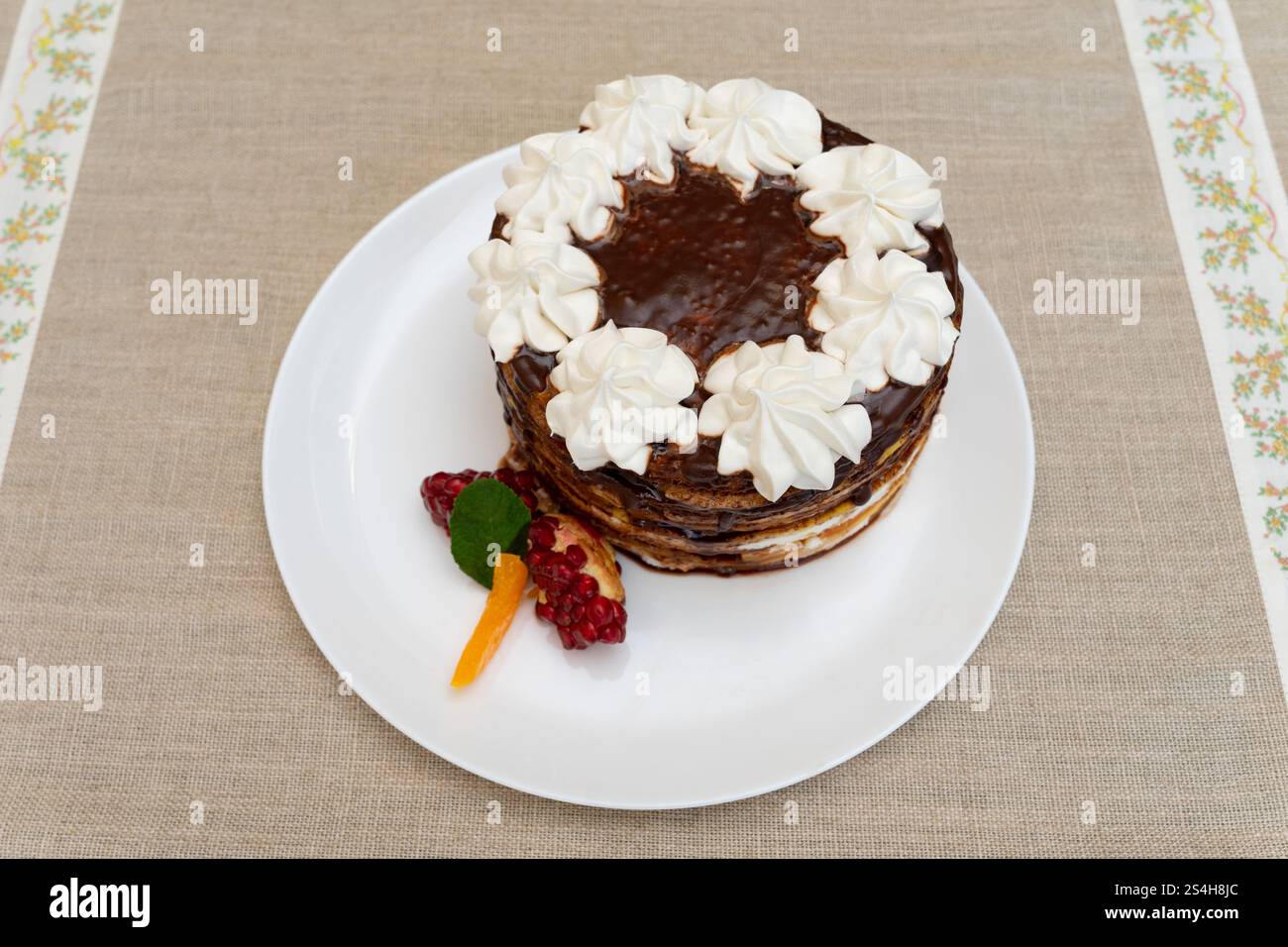 Una torta a strati finemente lavorata poggia su un piatto bianco. Foto Stock