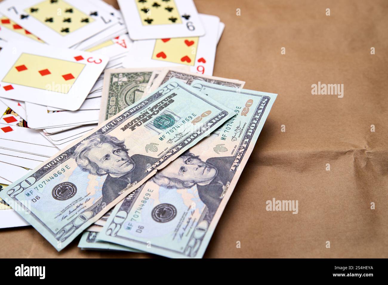 Un mucchio di dollari e un mazzo di carte da poker sparse su un tavolo Foto Stock