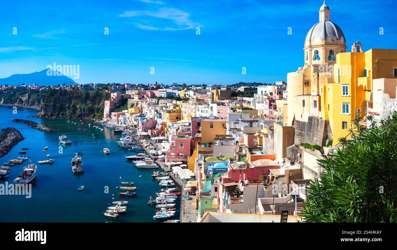 Viaggi in Italia e luoghi di interesse. L'isola più pittoresca e colorata - la bellissima Procida nel golfo di Napoli. Vista panoramica del porto di Corricella con chiesa gialla Foto Stock