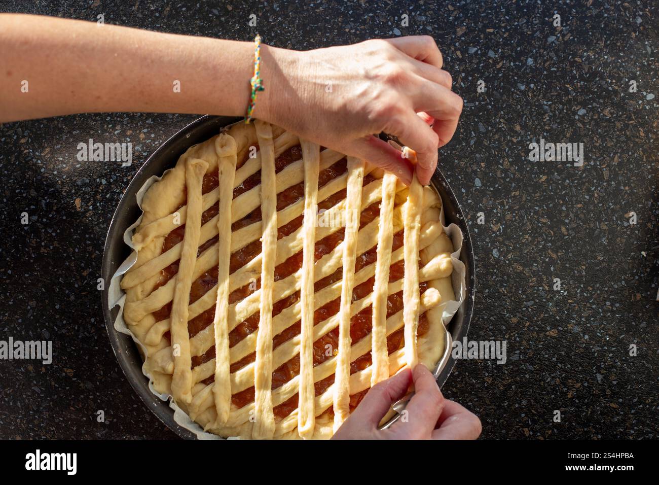 Preparazione di una torta dolce, stendere le strisce di impasto a reticolo sopra il ripieno dolce, visto dall'alto. Foto Stock