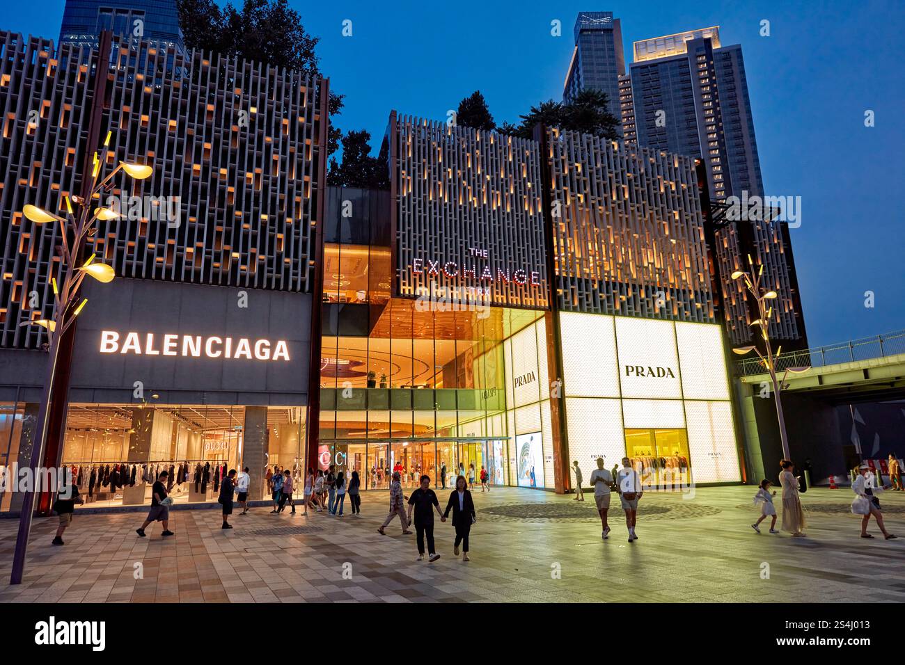 Le persone camminano di fronte all'illuminato Exchange TRX, un lussuoso centro commerciale nel quartiere di Tun Razak Exchange. Kuala Lumpur, Malesia. Foto Stock