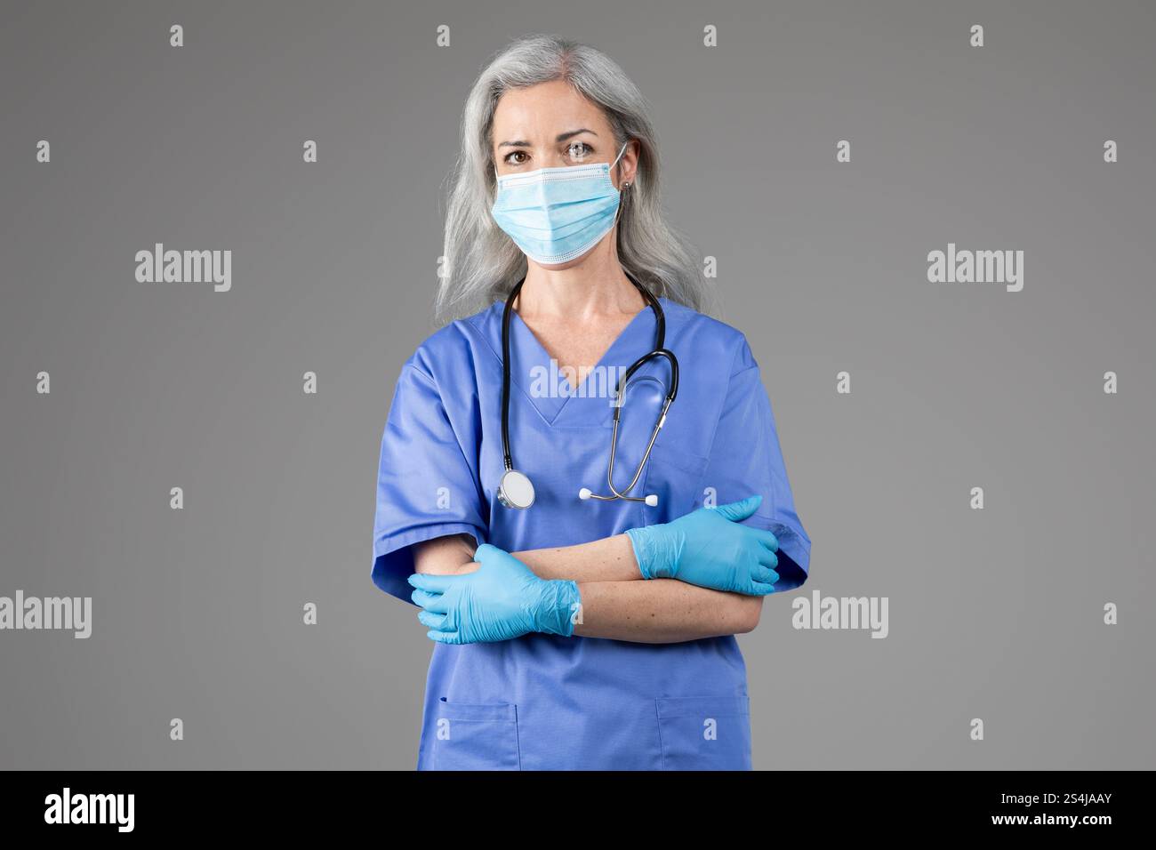 Medico di mezza età in scrub con maschera protettiva e guanti Foto Stock