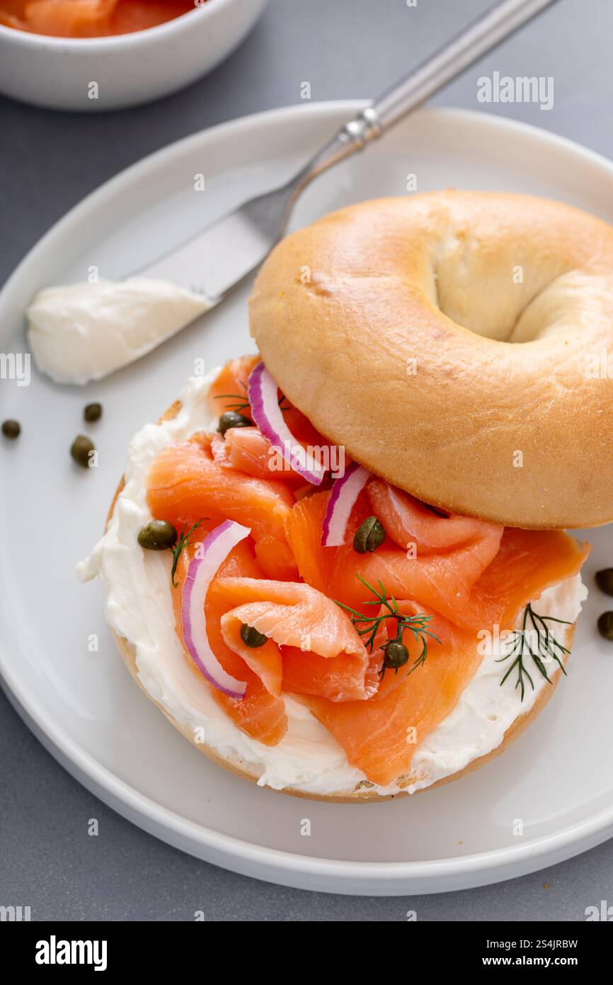 Bagel di salmone affumicato placcato con formaggio spalmabile su un moderno tavolo da cucina Foto Stock