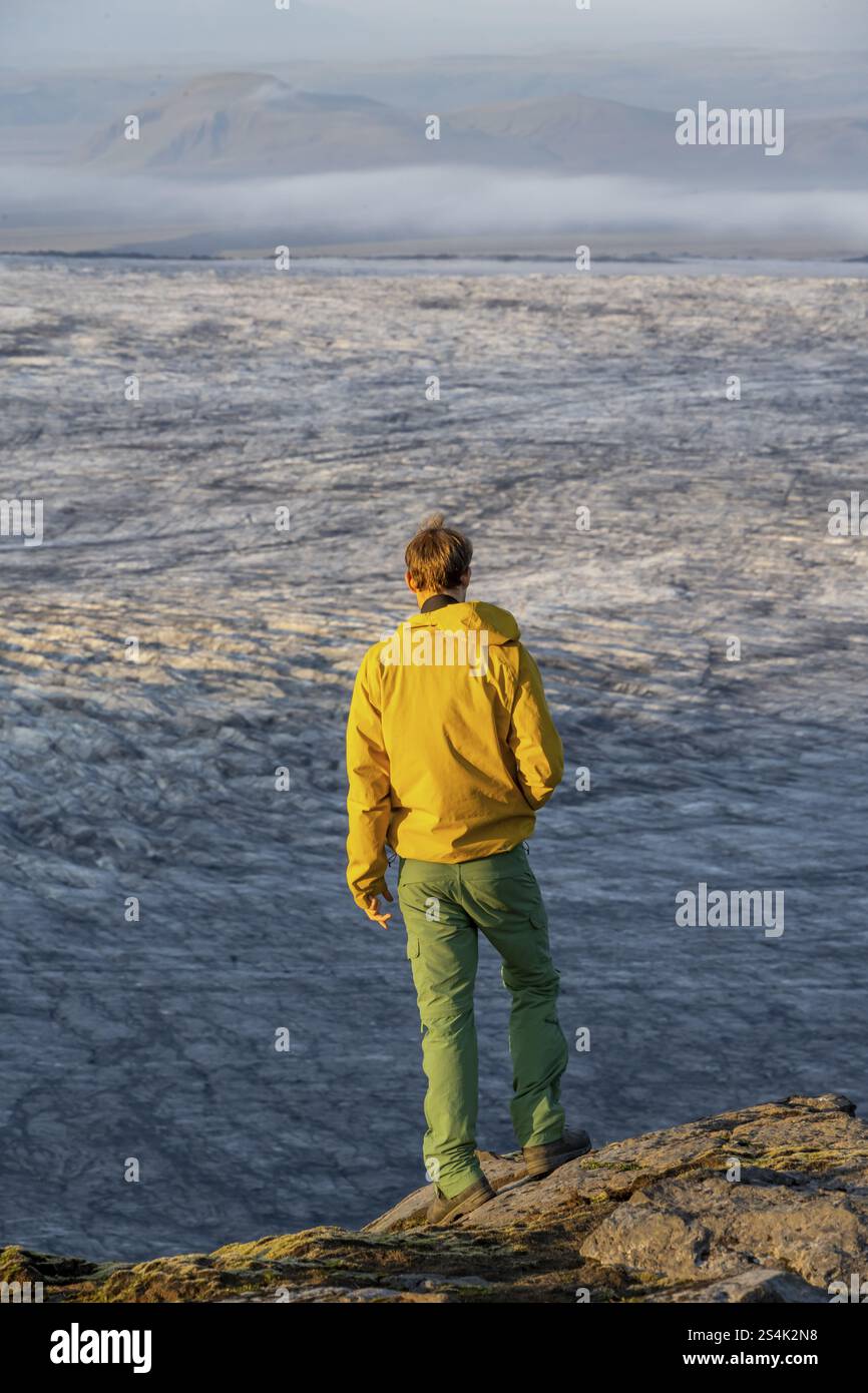 Giovanotto, turista di fronte al ghiacciaio, alla luce della sera, lingue del ghiacciaio Koetlujoekull, Myrdalsjoekull glacier Pakgil, Islanda, Europa Foto Stock