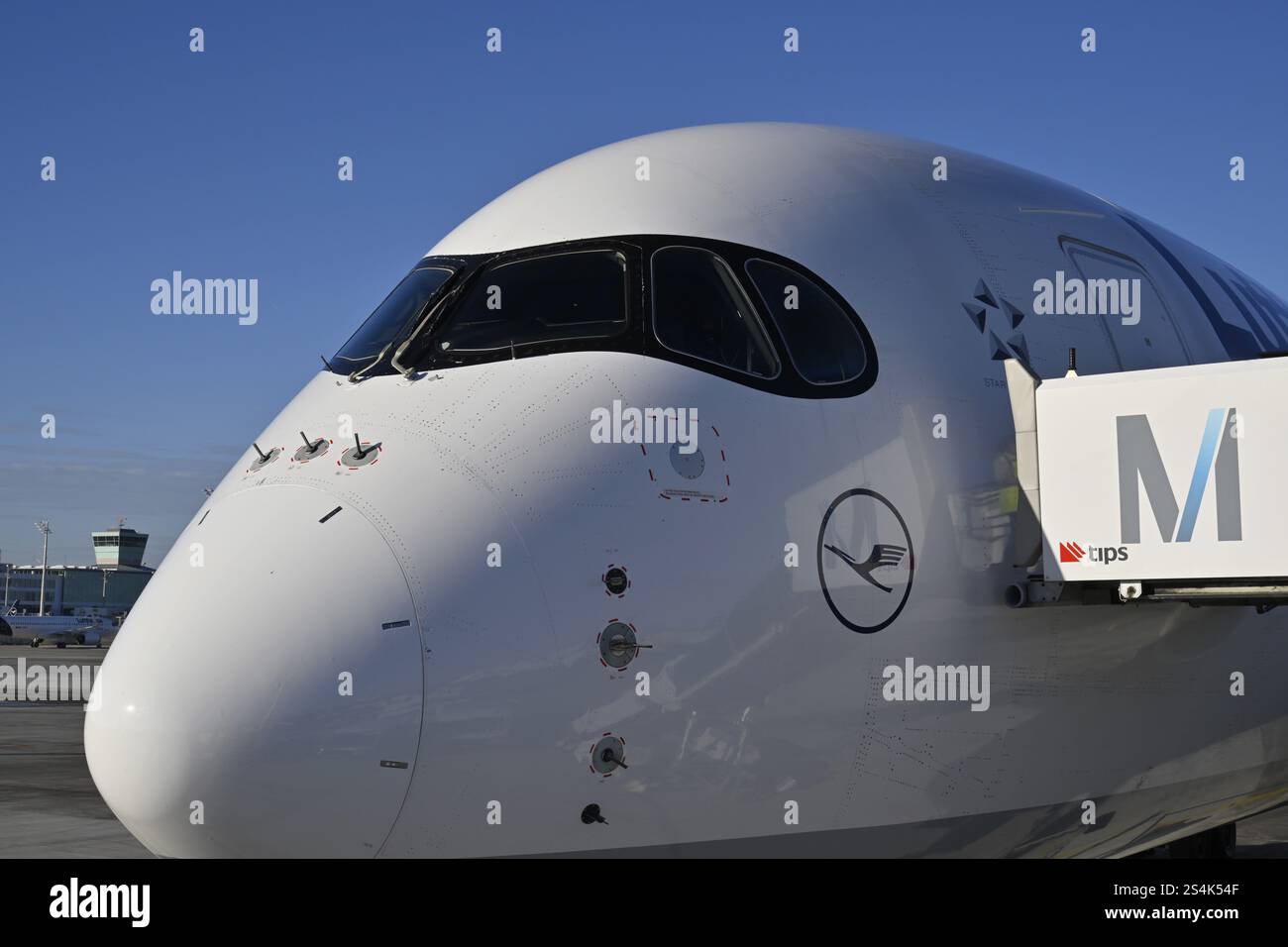 Lufthansa Airbus A350-900, cabina di pilotaggio e cabina con ponte di imbarco passeggeri al momento del check-in di fronte al Terminal 2 con cielo blu, Apron 2 East, T Foto Stock