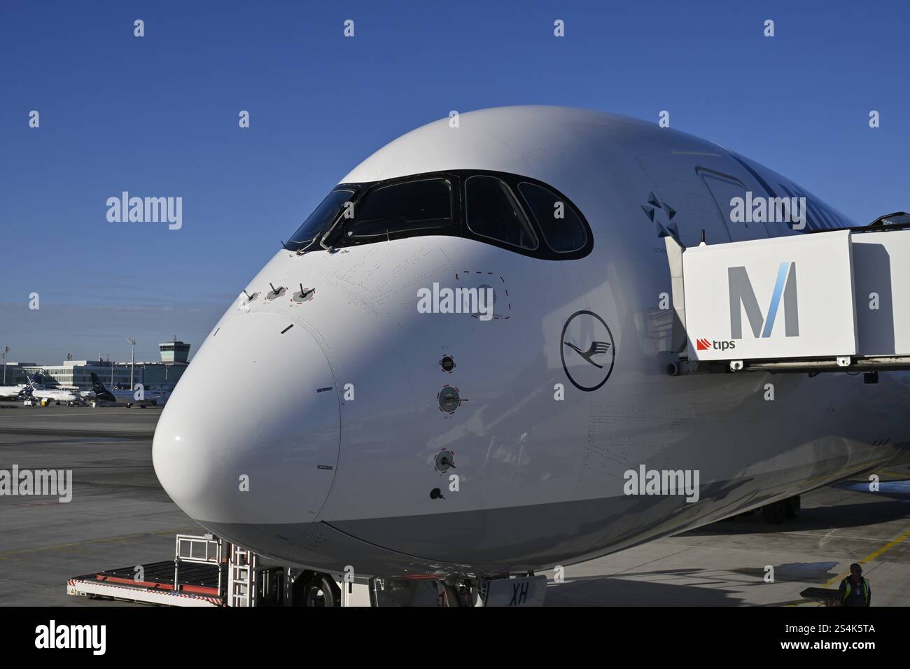 Lufthansa Airbus A350-900, cabina di pilotaggio e cabina con ponte di imbarco passeggeri al momento del check-in di fronte al Terminal 2 con cielo blu, Apron 2 East, T Foto Stock