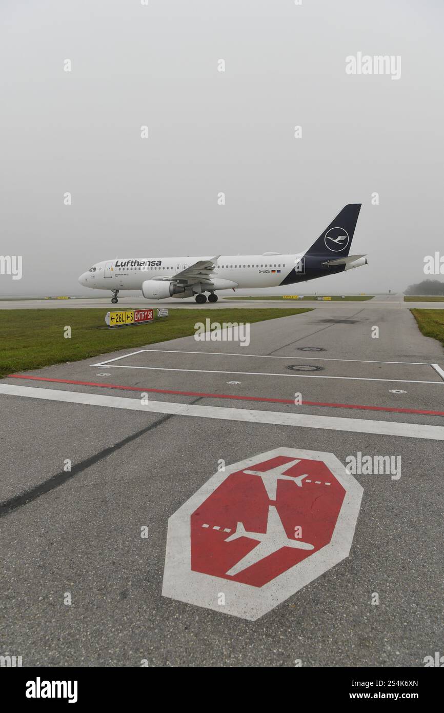 Lufthansa Airbus A320-200 rullante su pista di rullaggio nebbia con segnaletica di stop, aeroporto di Monaco, alta Baviera, Baviera, Germania, Europa Foto Stock