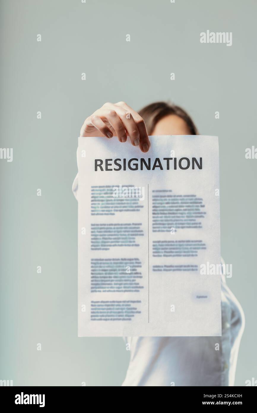 Donna d'affari con una lettera di dimissioni davanti al suo volto, che contempla un significativo cambiamento di carriera e la decisione di lasciare il suo lavoro per New o Foto Stock