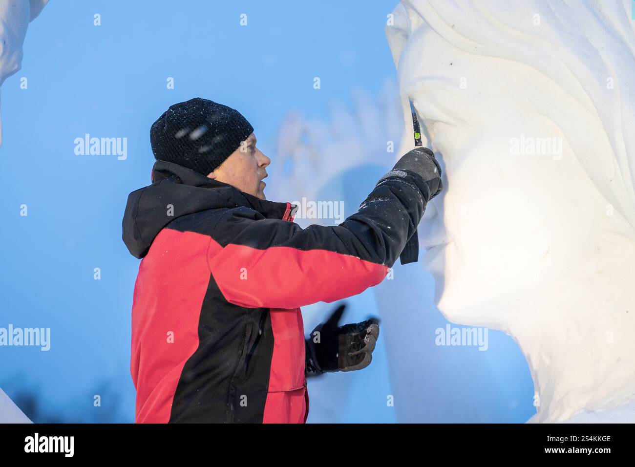 Un maestro artista realizza una scultura sulla neve in una mattina d'inverno - il volto di una donna della neve dalla neve per strada. Krasnoyarsk, Russia, 11 gennaio 2025. Foto Stock