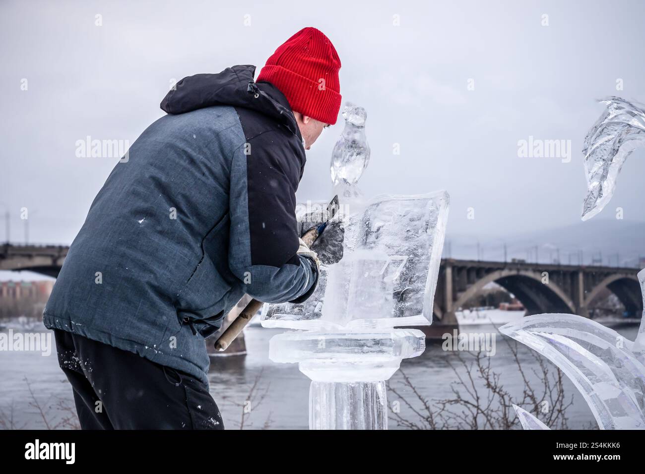 L'autore dello scultore crea elementi di scultura di ghiaccio, in inverno sulla strada al centro vicino al ponte sul fiume Yenisei Foto Stock