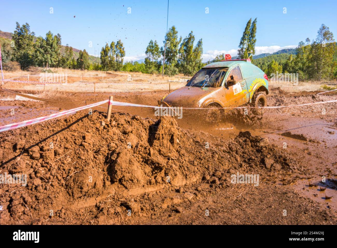 brivido delle corse fuoristrada. Un veicolo robusto si vede schizzare attraverso una pista fangosa, rimuovendo sporcizia e acqua. Foto Stock