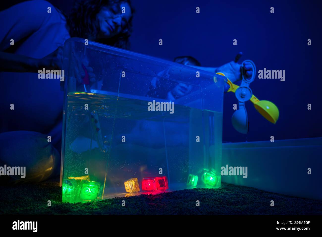 Bambino e terapista in camera stimolante sensoriale, Black snoezelen. Bambino autistico che gioca con il terapista durante la sessione di terapia occupazionale. Foto Stock