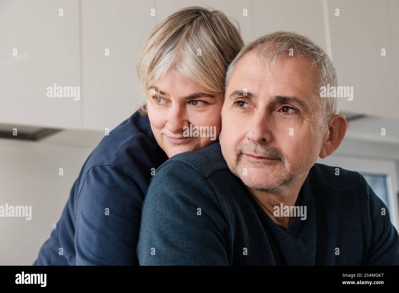 Una coppia senior abbraccia, mostrando affetto e calore in un ambiente accogliente, le loro espressioni riflettono il piacere e l'amore, mettendo in risalto il beau Foto Stock