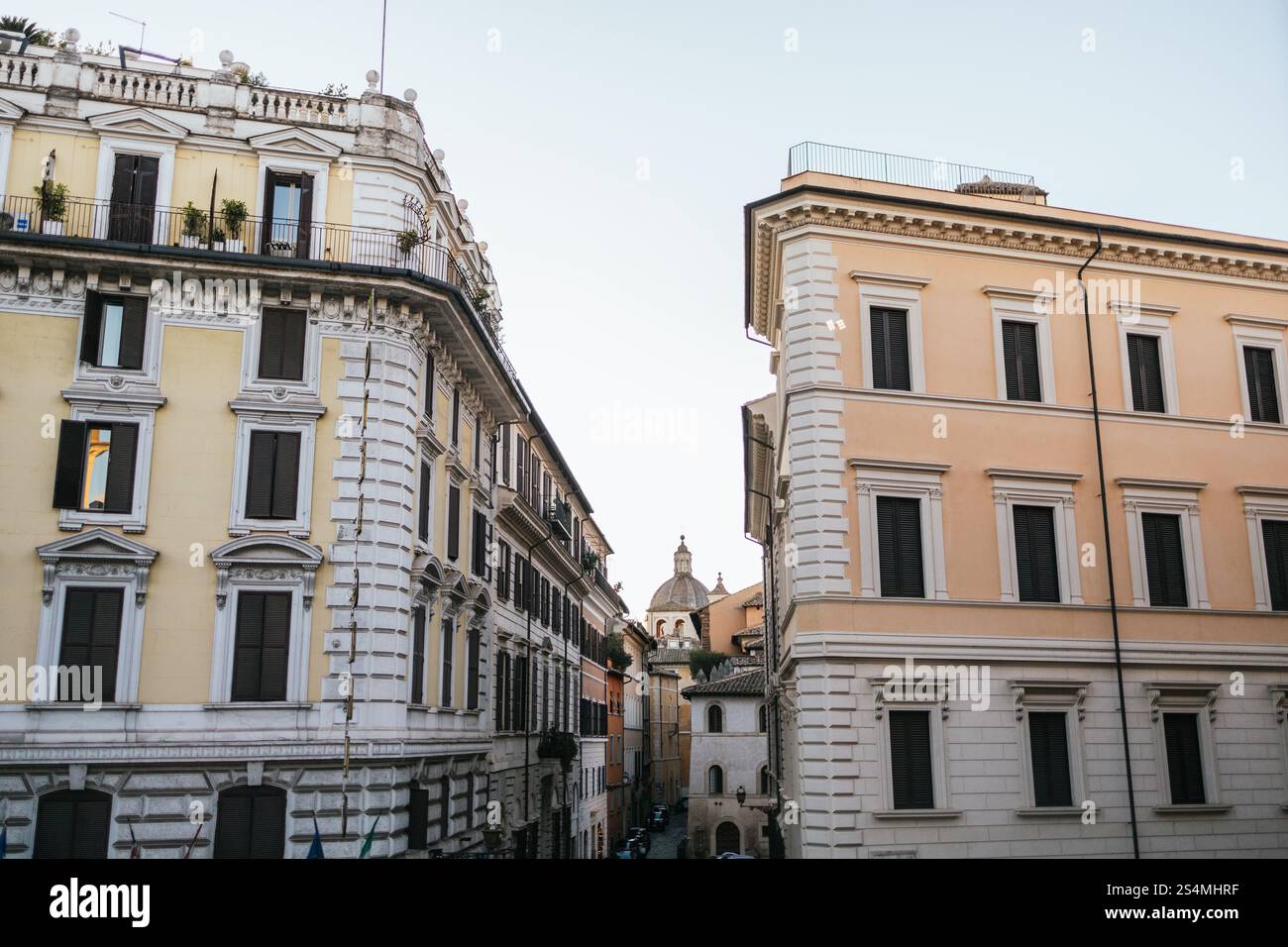 Elegante architettura romana con facciate color pastello e dettagli decorati sotto un cielo limpido che catturano il fascino storico e l'eleganza senza tempo degli sceni di Roma Foto Stock
