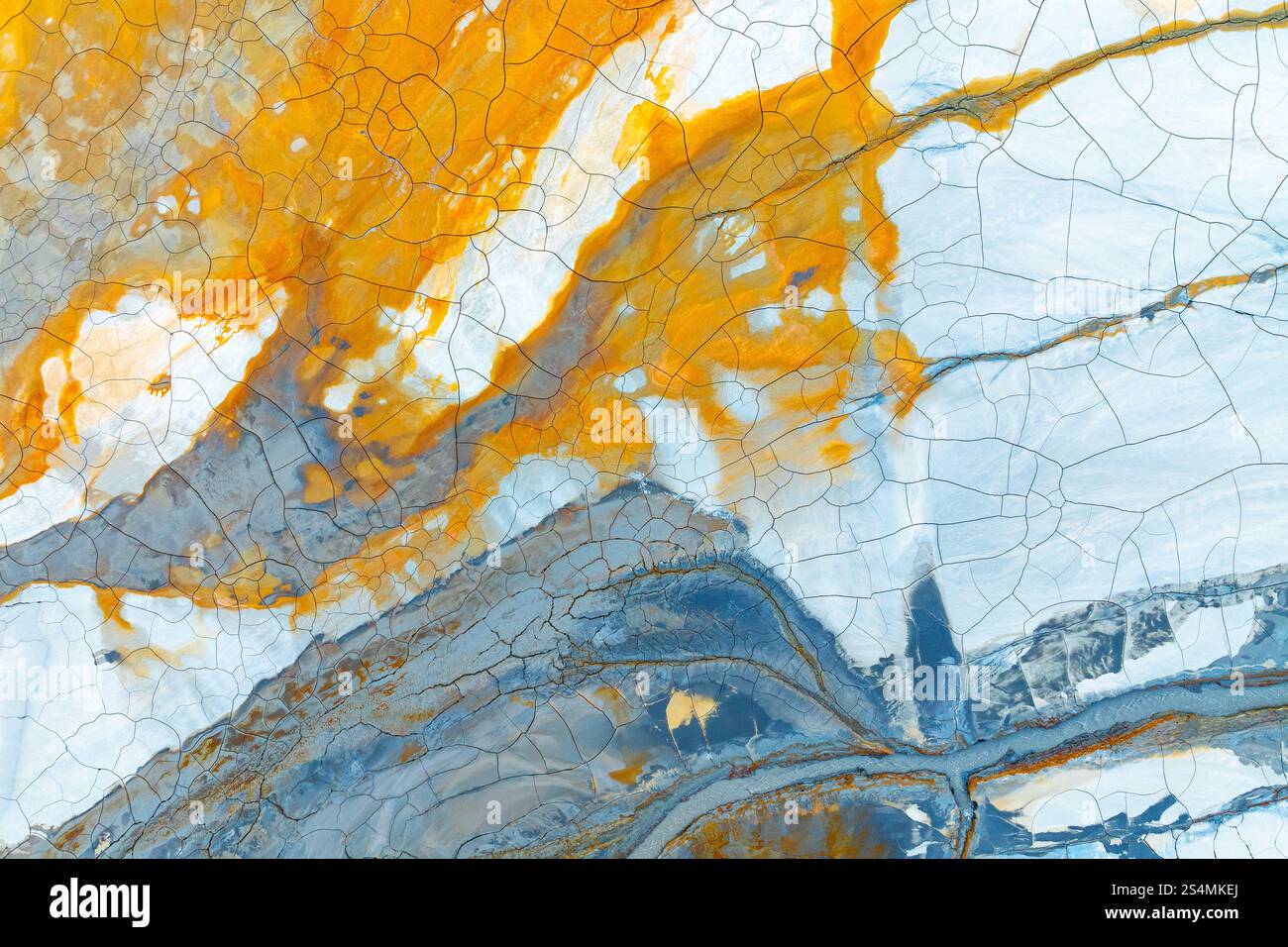 Un'accattivante immagine astratta che mostra fango multicolore con sorprendenti sfumature arancione, blu e bianco, le texture crepe creano un'intricata e bellissima fu Foto Stock