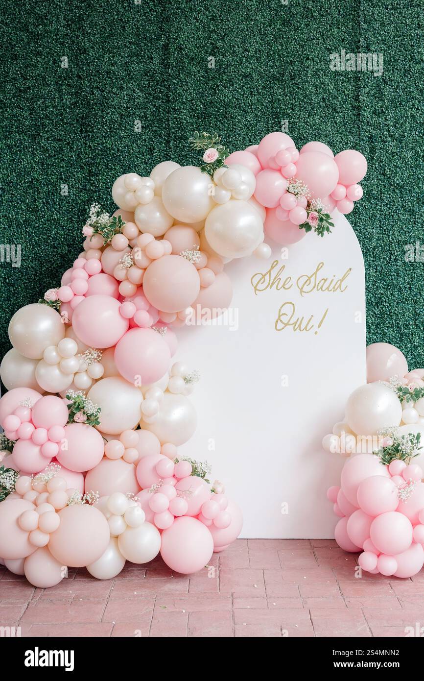Arco palloncino rosa e bianco con "She Said Oui!" e dettagli floreali. Foto Stock