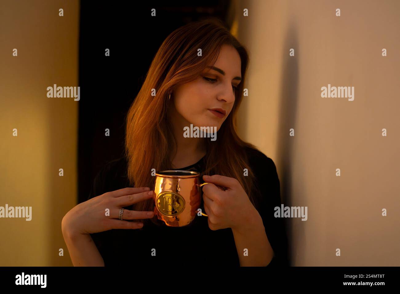 Giovane donna che si gode una bevanda calda in un ambiente accogliente Foto Stock