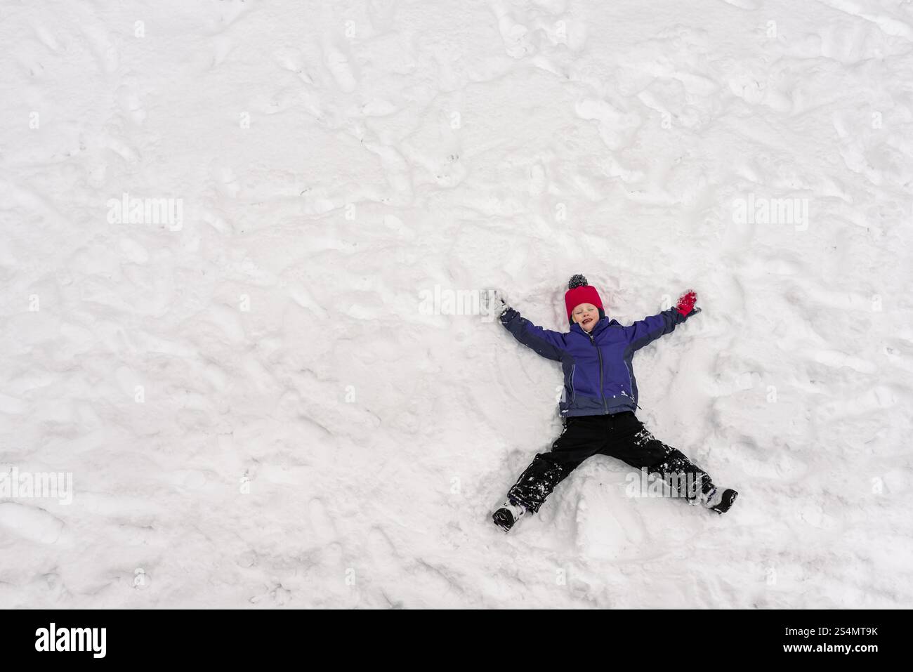 Vista dall'alto di una ragazza che crea angeli di neve con neve bianca fresca Foto Stock