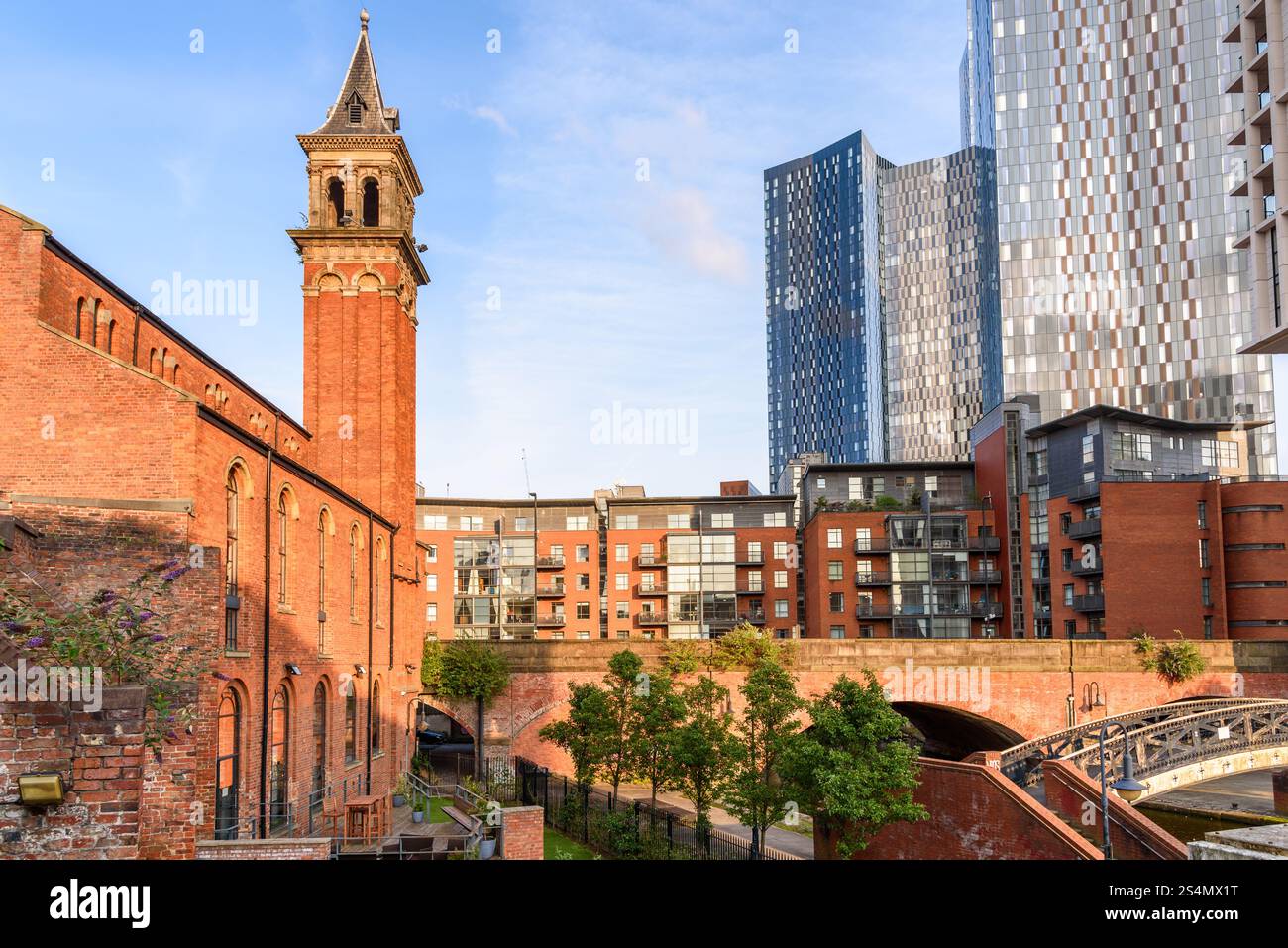 Moderni blocchi di appartamenti accanto a edifici in mattoni rinnovati lungo un canale a Castlefield, Manchester, al tramonto in estate Foto Stock