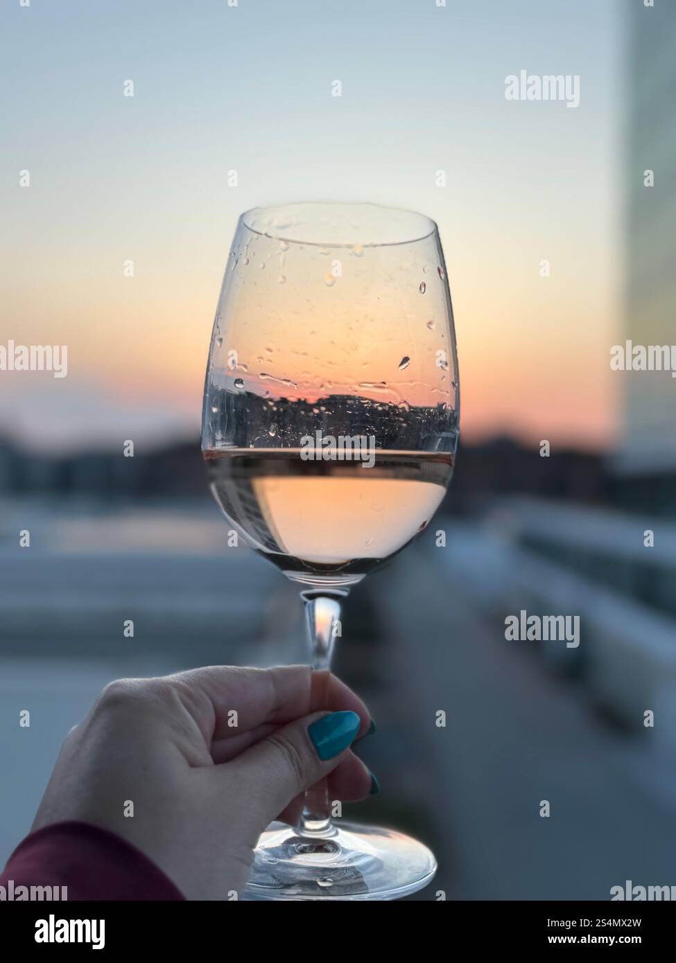 Riflessi al tramonto in un bicchiere di vino rosa Foto Stock