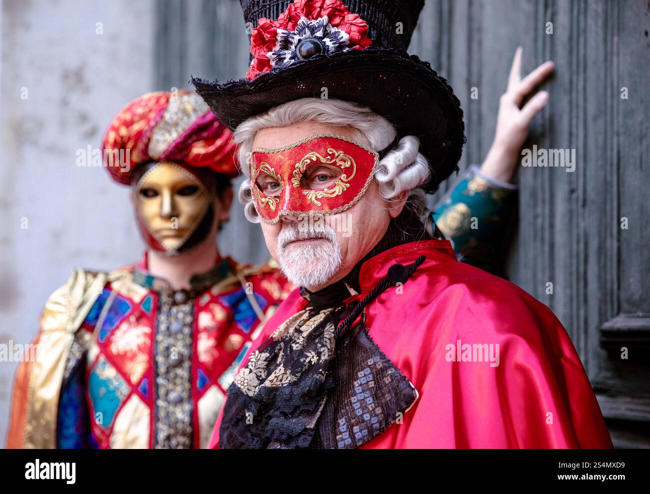 Uomini caucasici maturi in costumi veneziani con maschere a un'elega Foto Stock