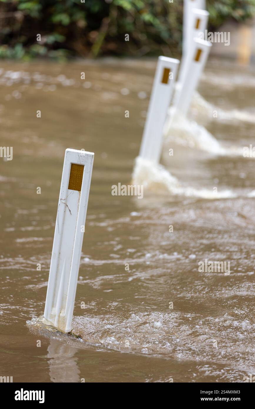 Posti stradali allagati nelle acque in aumento che si muovono rapidamente Foto Stock