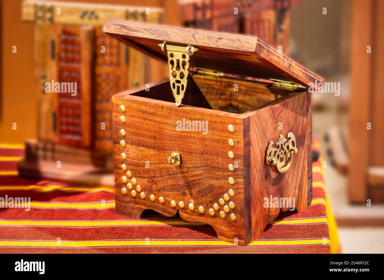 Una scatola omanita in legno artigianale con intricati dettagli in ottone e borchie dorate, che mostra la ricca tradizione e la maestria degli artigiani omaniti. Foto Stock Una scatola omanita in legno artigianale con intricati dettagli in ottone e borchie dorate, che mostra la ricca tradizione e la maestria degli artigiani omaniti. Foto Stock