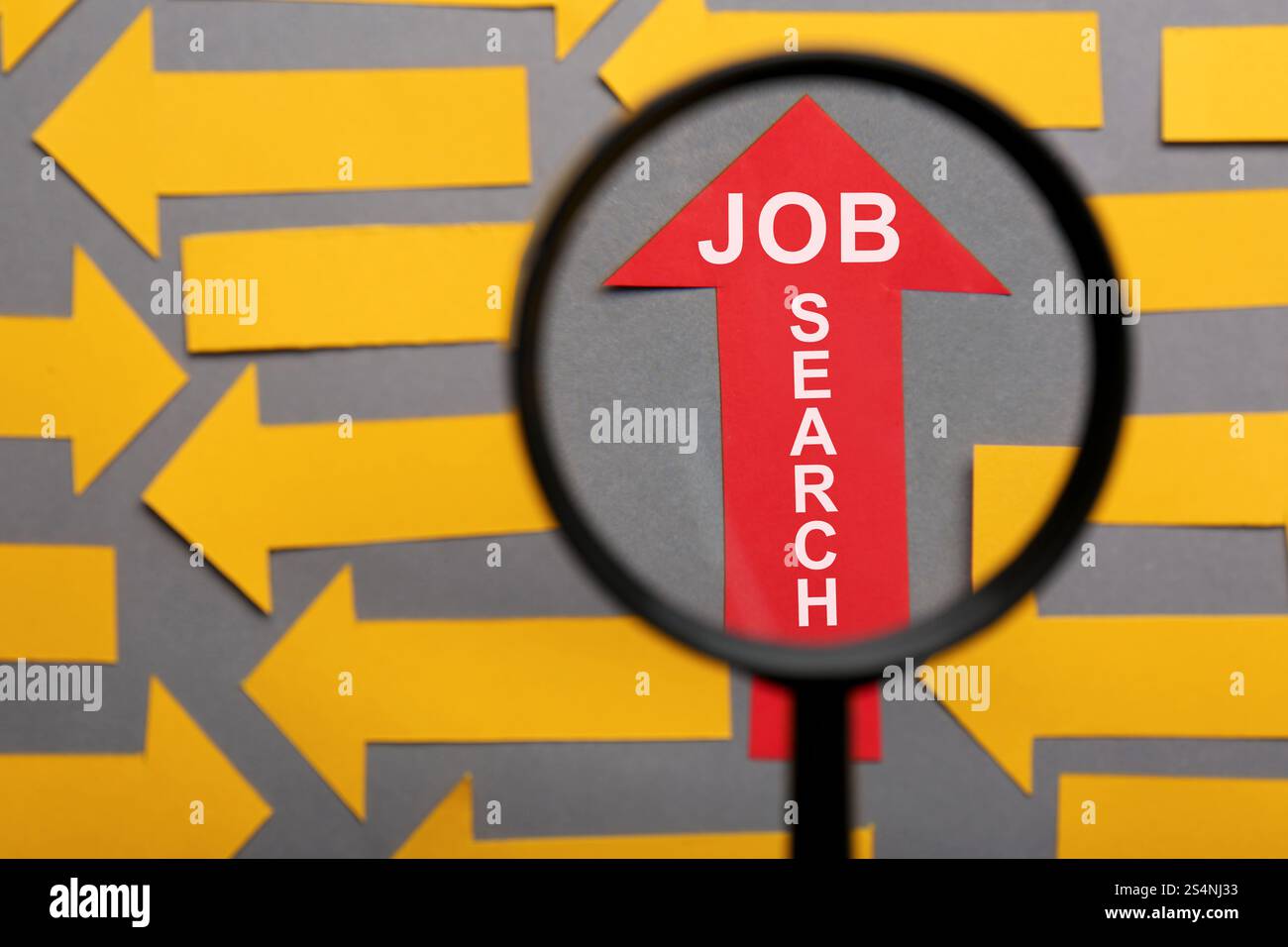 Concetto di ricerca lavoro. Freccia di carta rossa con le parole tra quelle arancioni su sfondo grigio, vista attraverso la lente di ingrandimento Foto Stock