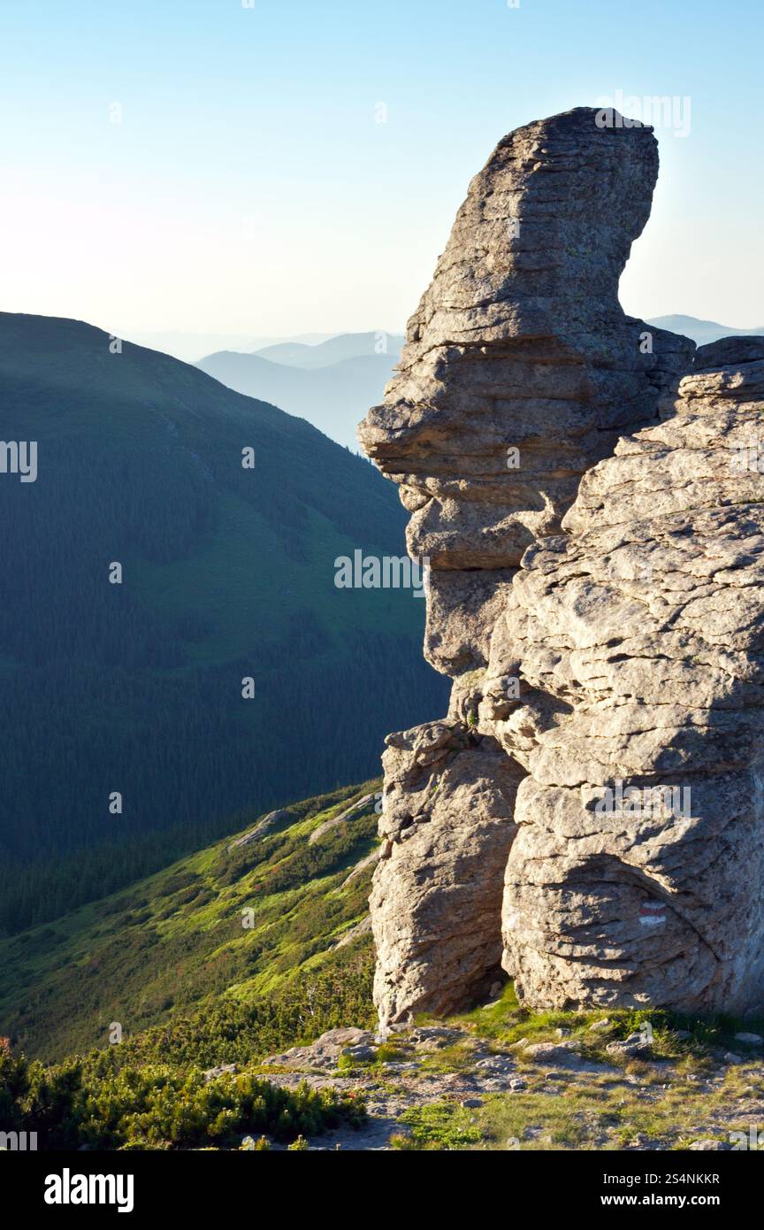 Big stony figura nel volto umano formano sulla sera montagna cresta Foto Stock