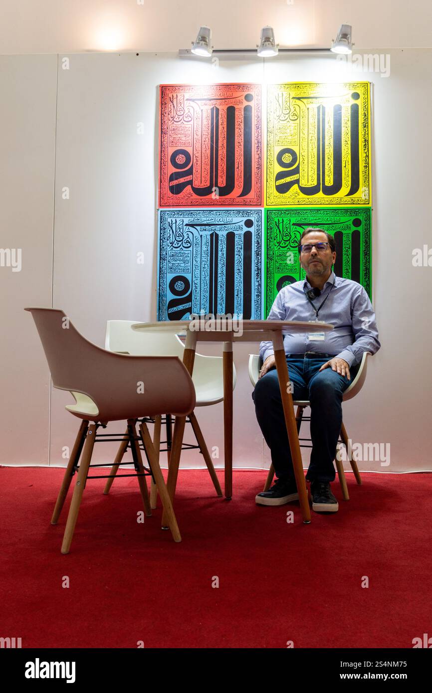 Una persona siede a un tavolo di fronte alla colorata arte muraria islamica di Algeri, Algeria. Foto Stock