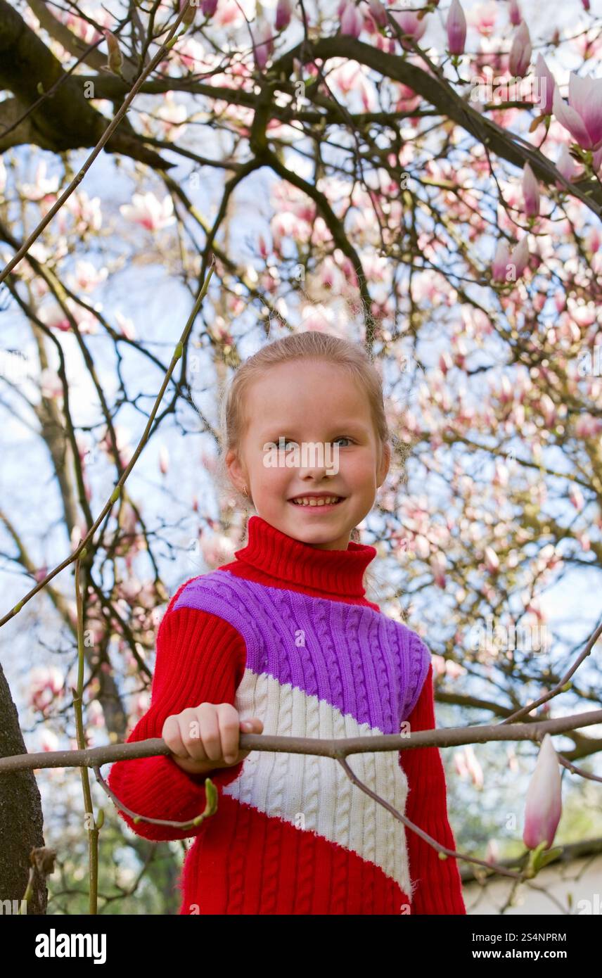Felice piccola ragazza ritratto vicino a fioritura albero di magnolia Foto Stock