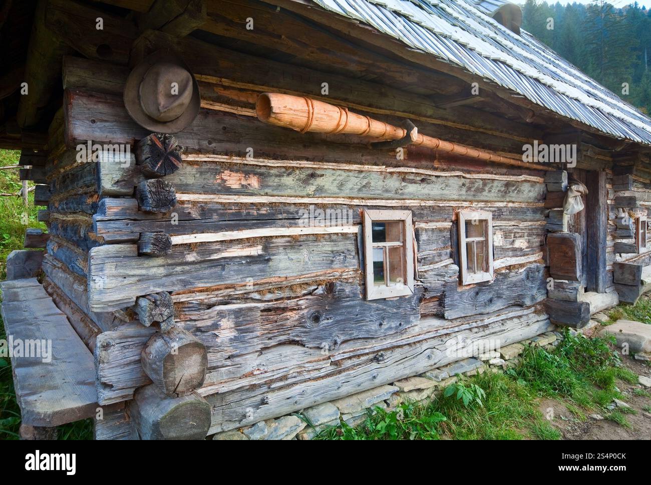 Vecchia casa in legno in autunno del villaggio di montagna (Carpazi , Ucraina) e trembita (Guzul musica tubo) sulla parete Foto Stock