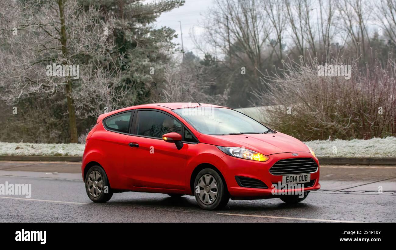 Milton Keynes, Regno Unito - 12 gennaio 2025: 2014 auto Ford Fiesta rossa che guida in una mattina fredda e ghiacciata Foto Stock