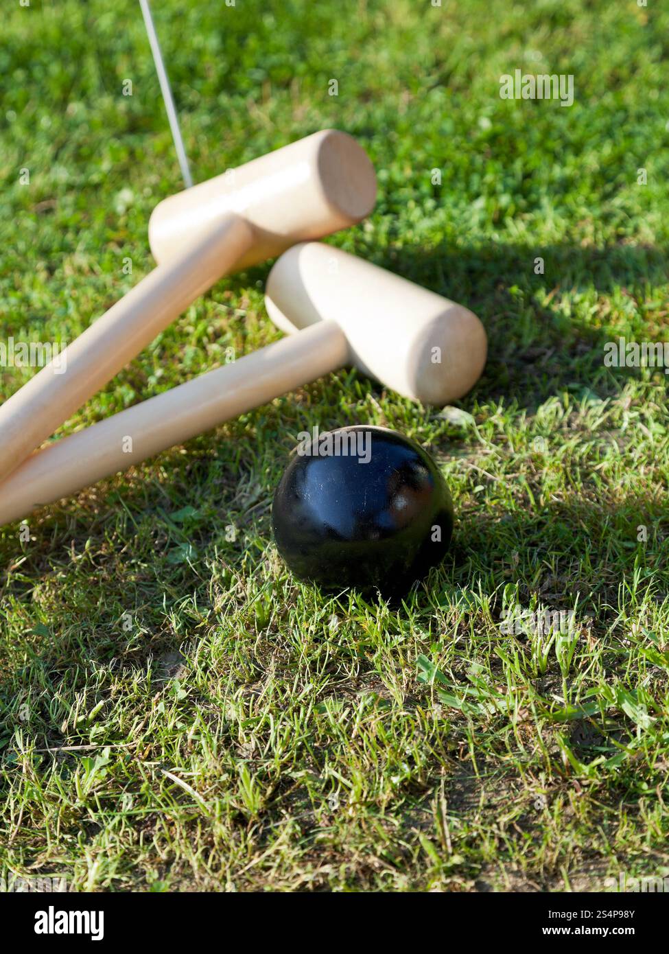 mazzuoli e palla nera in partita di croquet sul prato verde in estate Foto Stock