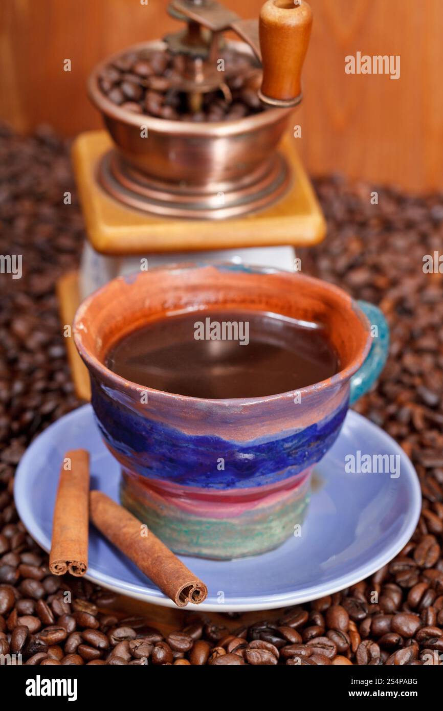 tazza di caffè e chicchi di caffè tostati con tritatutto manuale in rame retrò e primo piano alla cannella Foto Stock