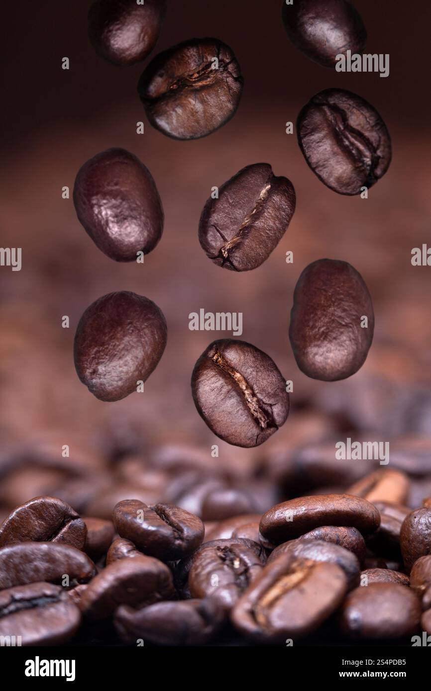 La caduta di chicchi di caffè tostati sul caffè nero lo sfondo con il primo piano di messa a fuoco Foto Stock