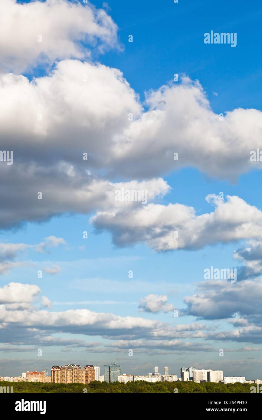 Case urbane sotto grandi nuvole bianche nella primavera del cielo blu Foto Stock