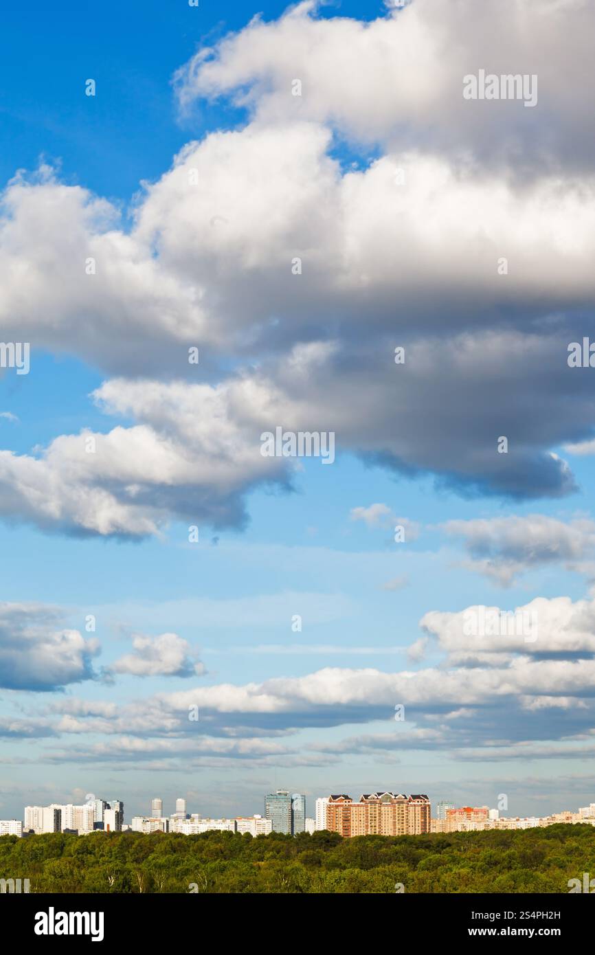 Città sotto grandi nuvole bianche nella primavera del cielo blu Foto Stock
