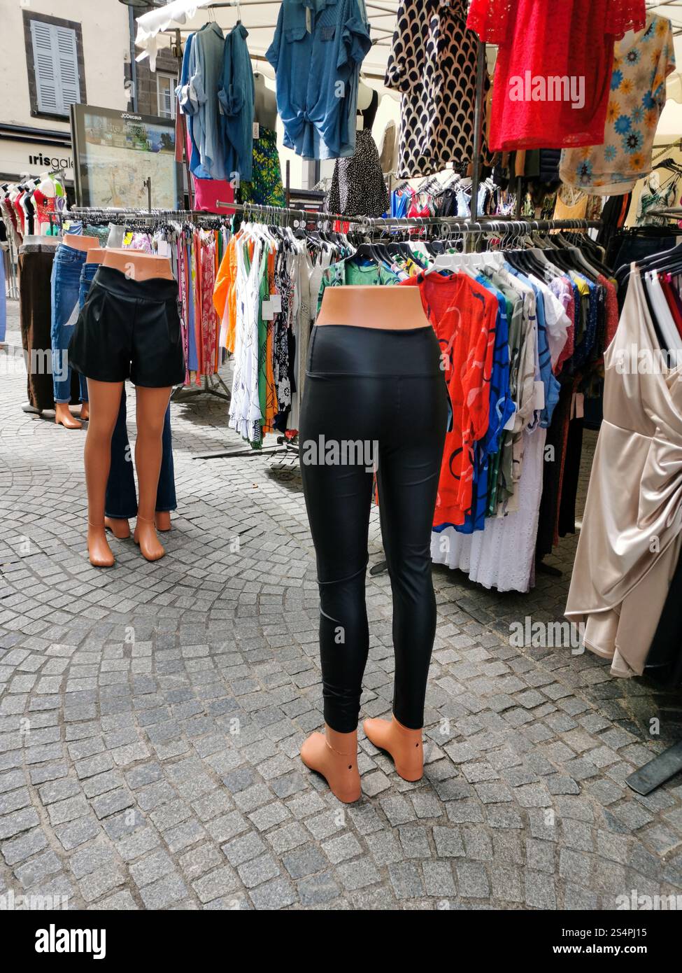 Un vivace mercato espone manichini vestiti con abiti eleganti e vari capi di abbigliamento colorati in mostra. L'atmosfera riflette un vivace shopping Foto Stock