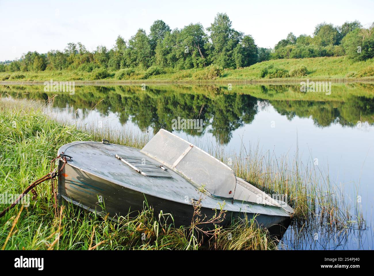 Vecchia barca sulla riva verde del piccolo fiume nel giorno di estate Foto Stock