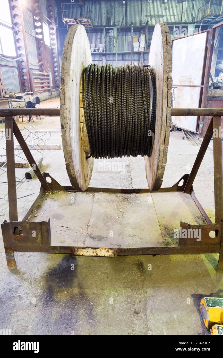 Industriale bobina in legno con fune di acciaio in magazzino officina Foto Stock
