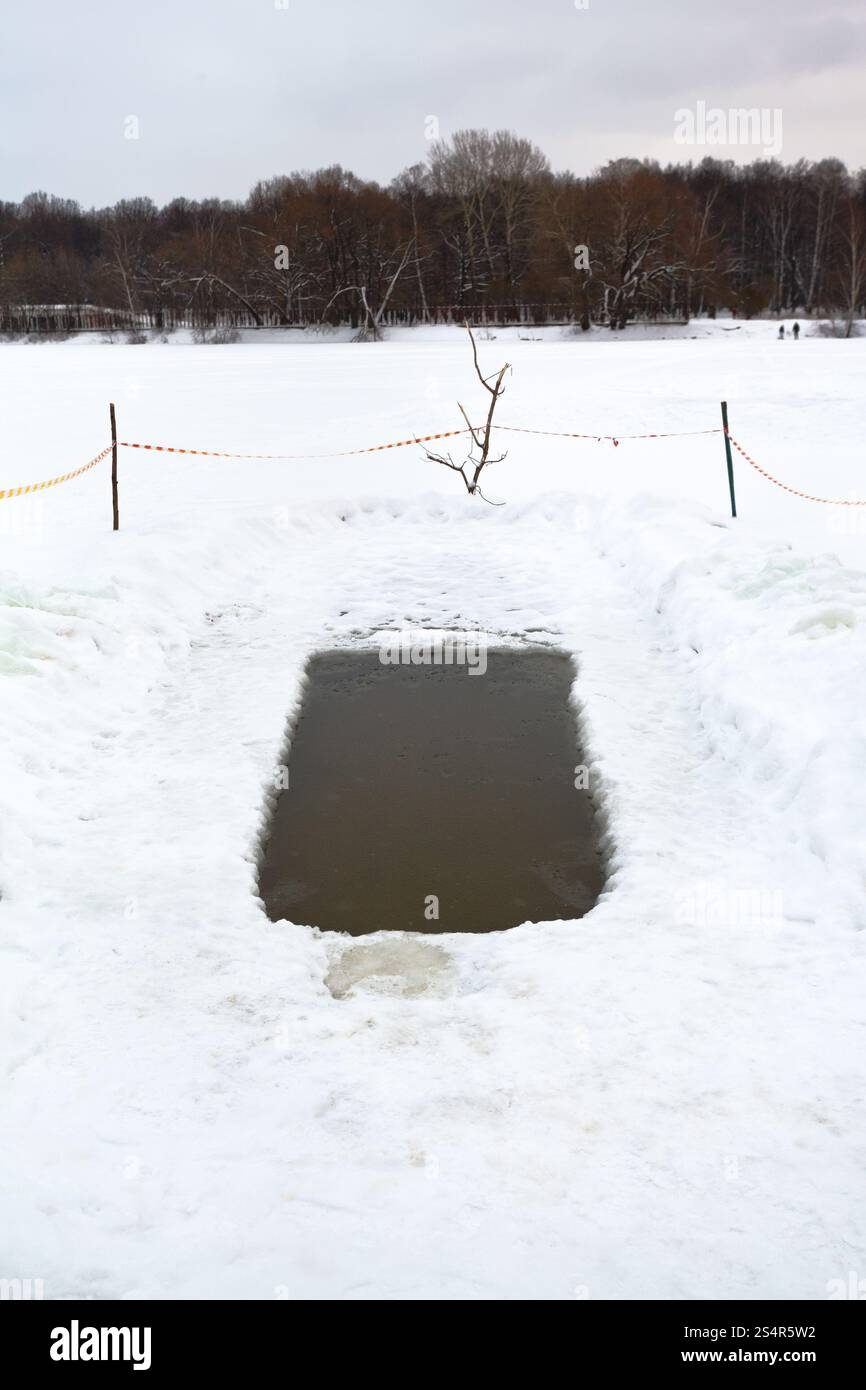 Foro di ghiaccio con acqua congelata nel fiume nella giornata invernale Foto Stock