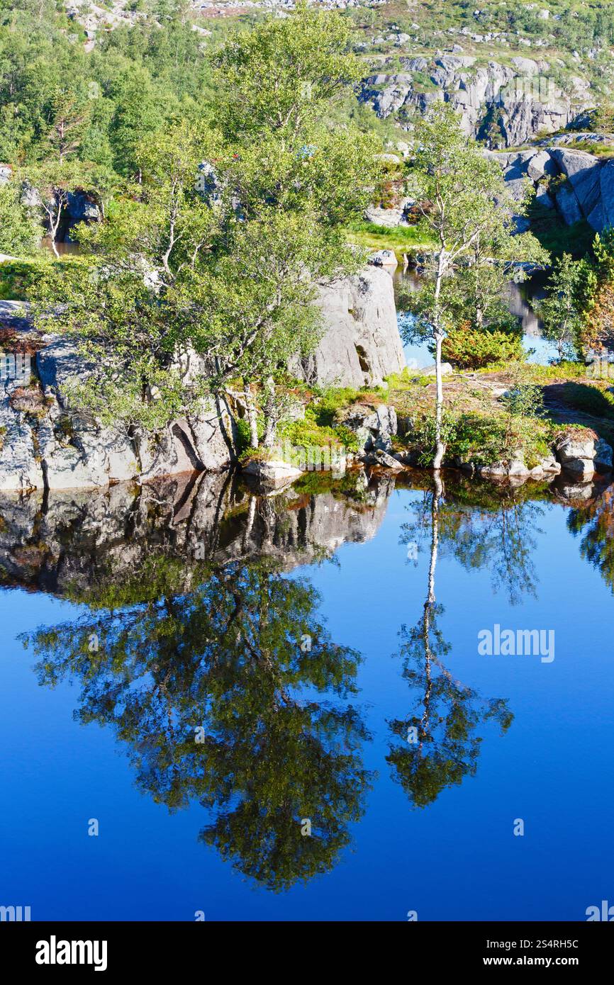Profondo blu piccola montagna Norvegia lago con spiaggia rocciosa Foto Stock