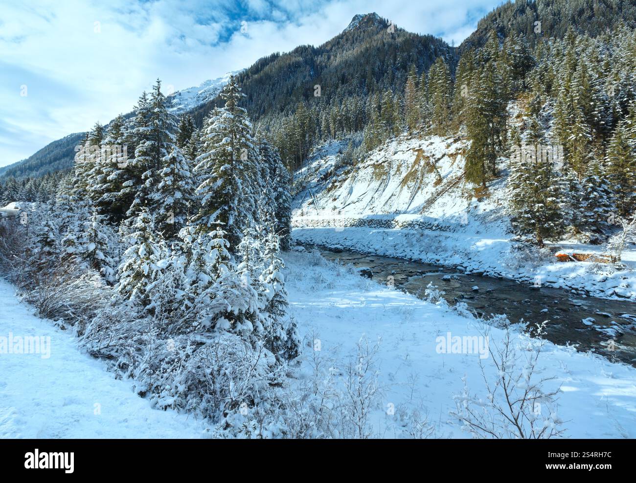 Fiume invernale con cespugli innevati e alberi sulla riva. Foto Stock