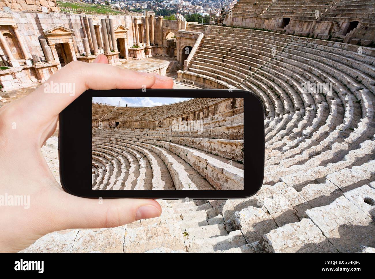Concetto di viaggio - turistica prendendo foto dell'arena nel grande teatro del Sud nella città antica Jerash in Giordania su gadget mobile Foto Stock